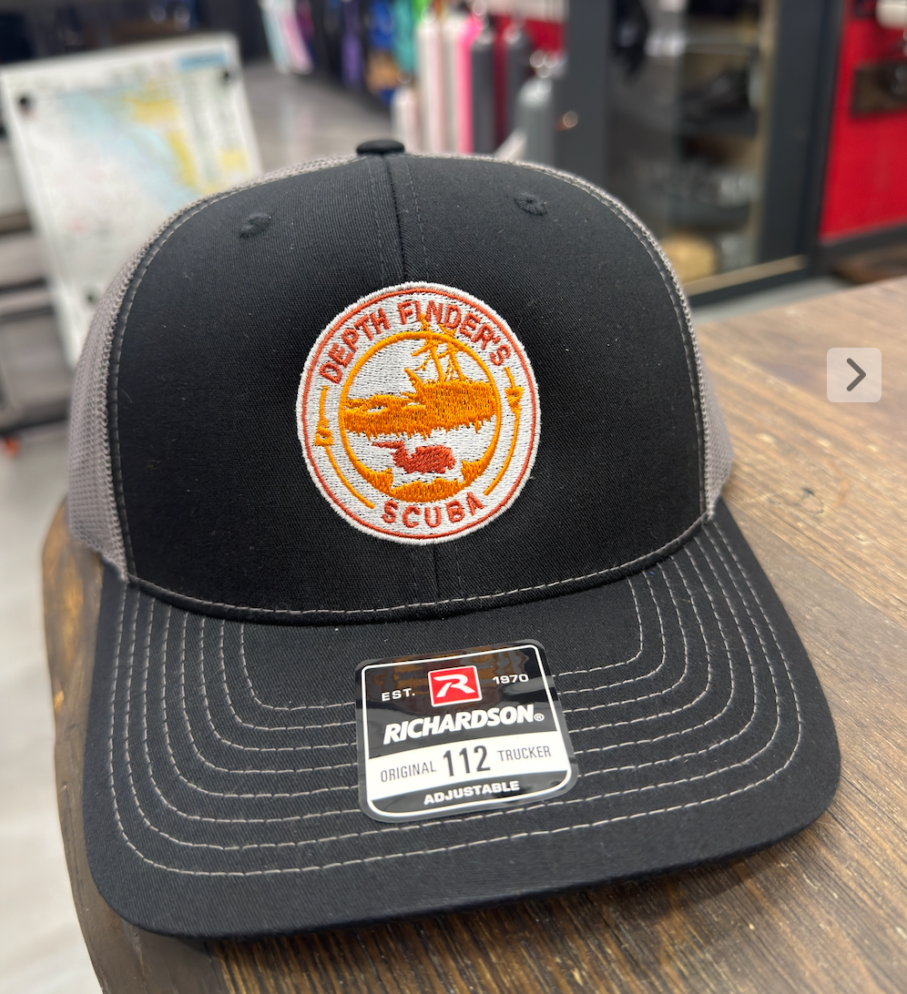 Black and gray cap with a logo on a wooden surface